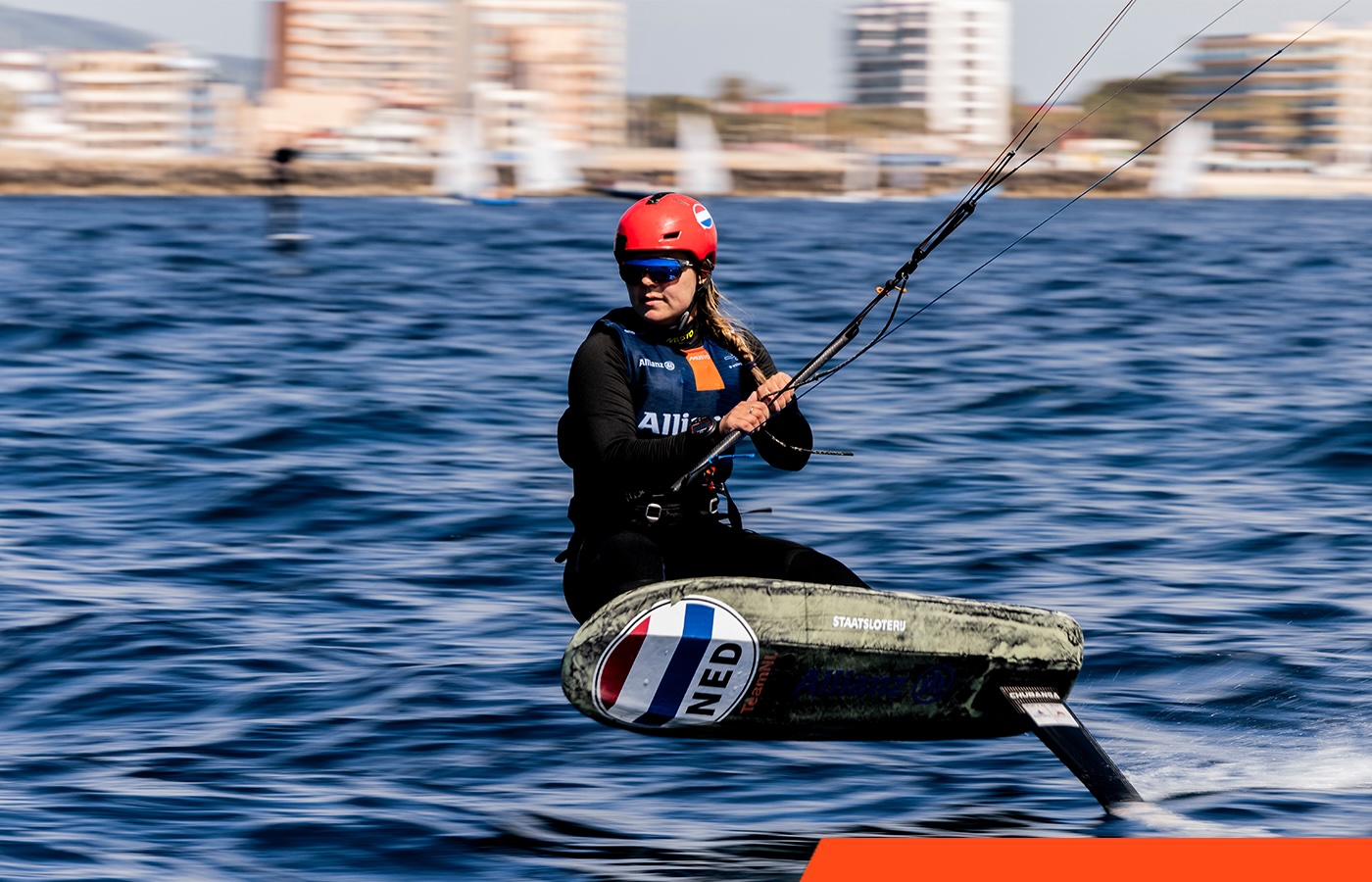 Jessie Kampman op haar kitefoil, met de Nederlandse vlag op het board